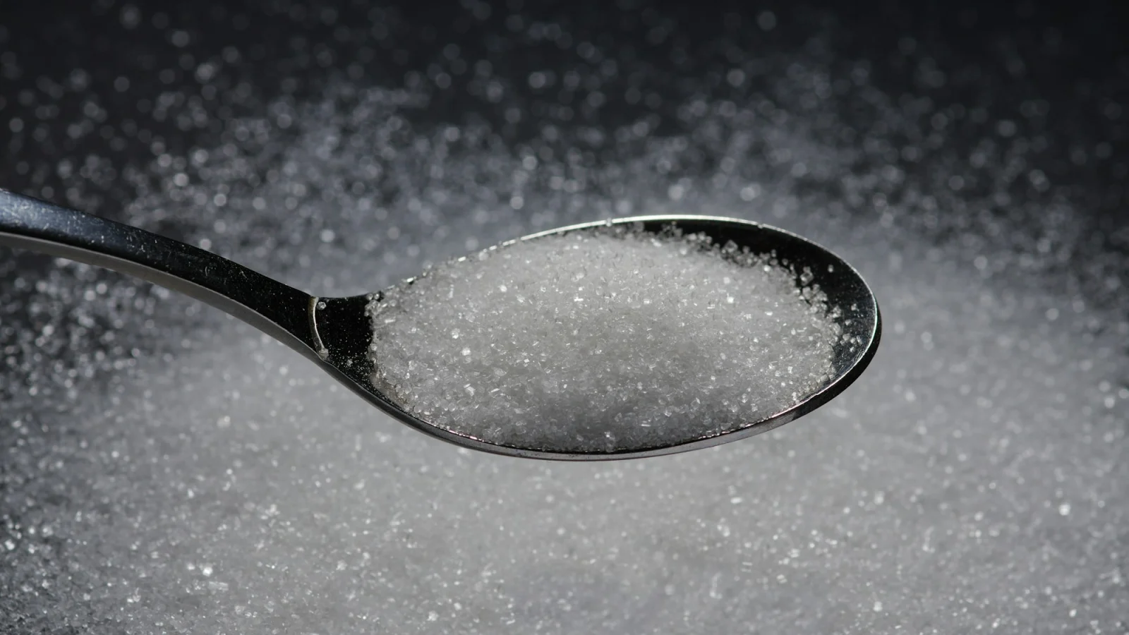 A spoon filled with sugar on top of a table