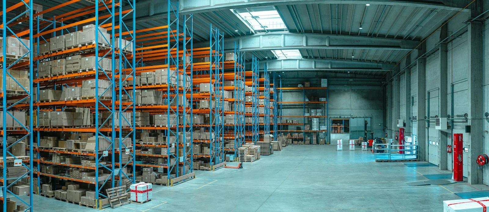 Tall blue metal shelving units filled with cardboard boxes in a large warehouse